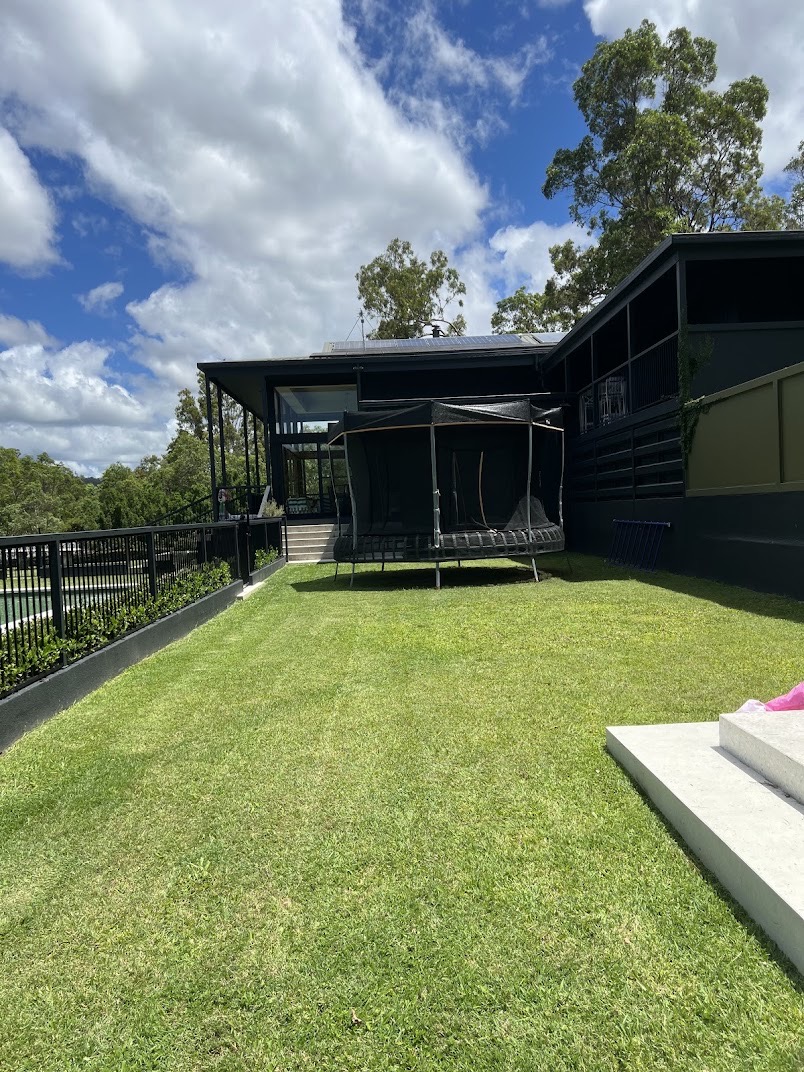 Backyard lawn freshly cut and edged along a retaining wall and hedge line