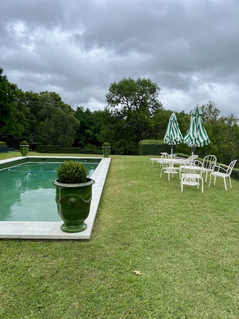 Manicured lawn surrounding a pool with clipped hedges and potted topiary