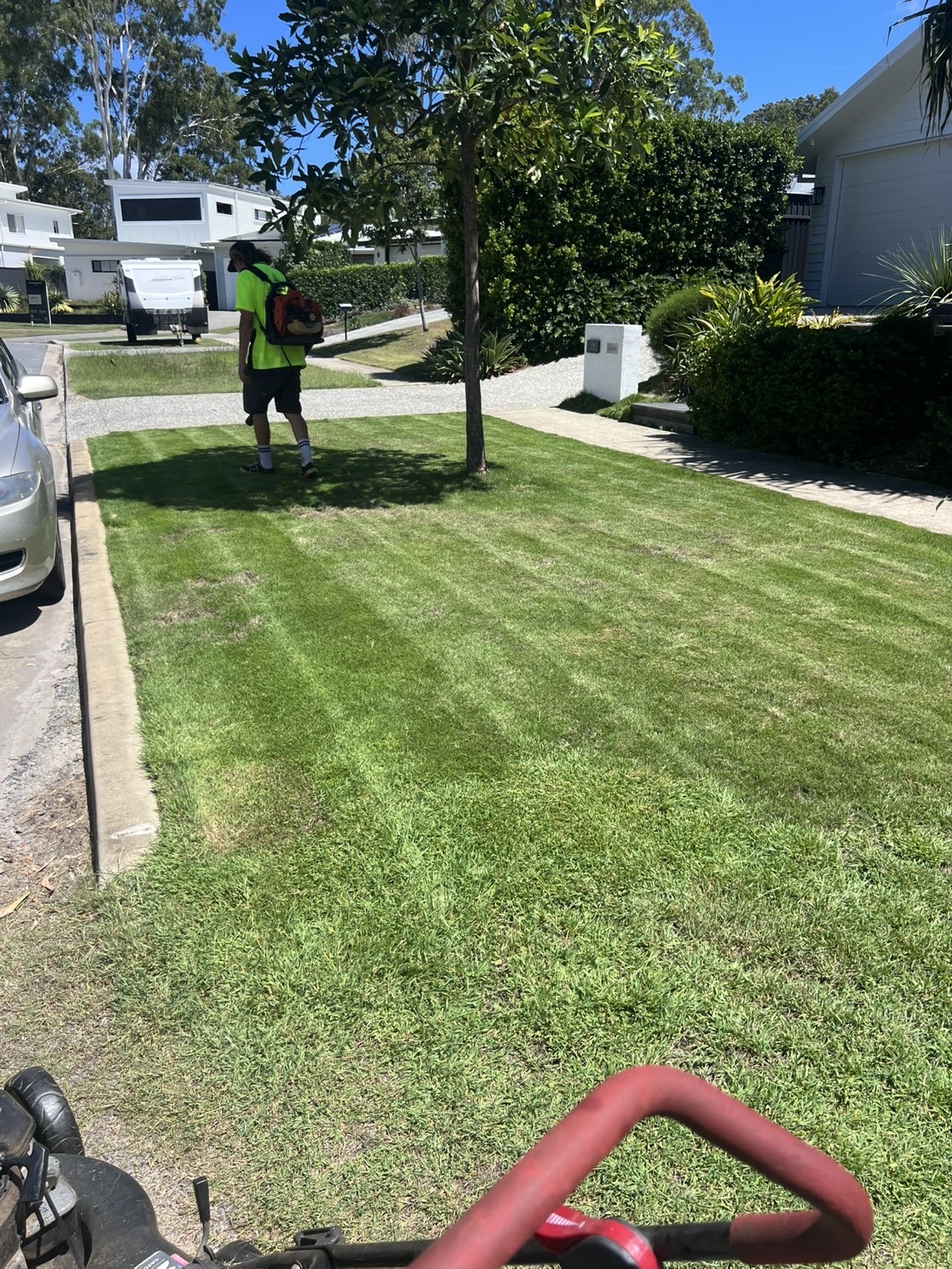 EastCoast Gardening team member edging a freshly striped front lawn on a Gold Coast street