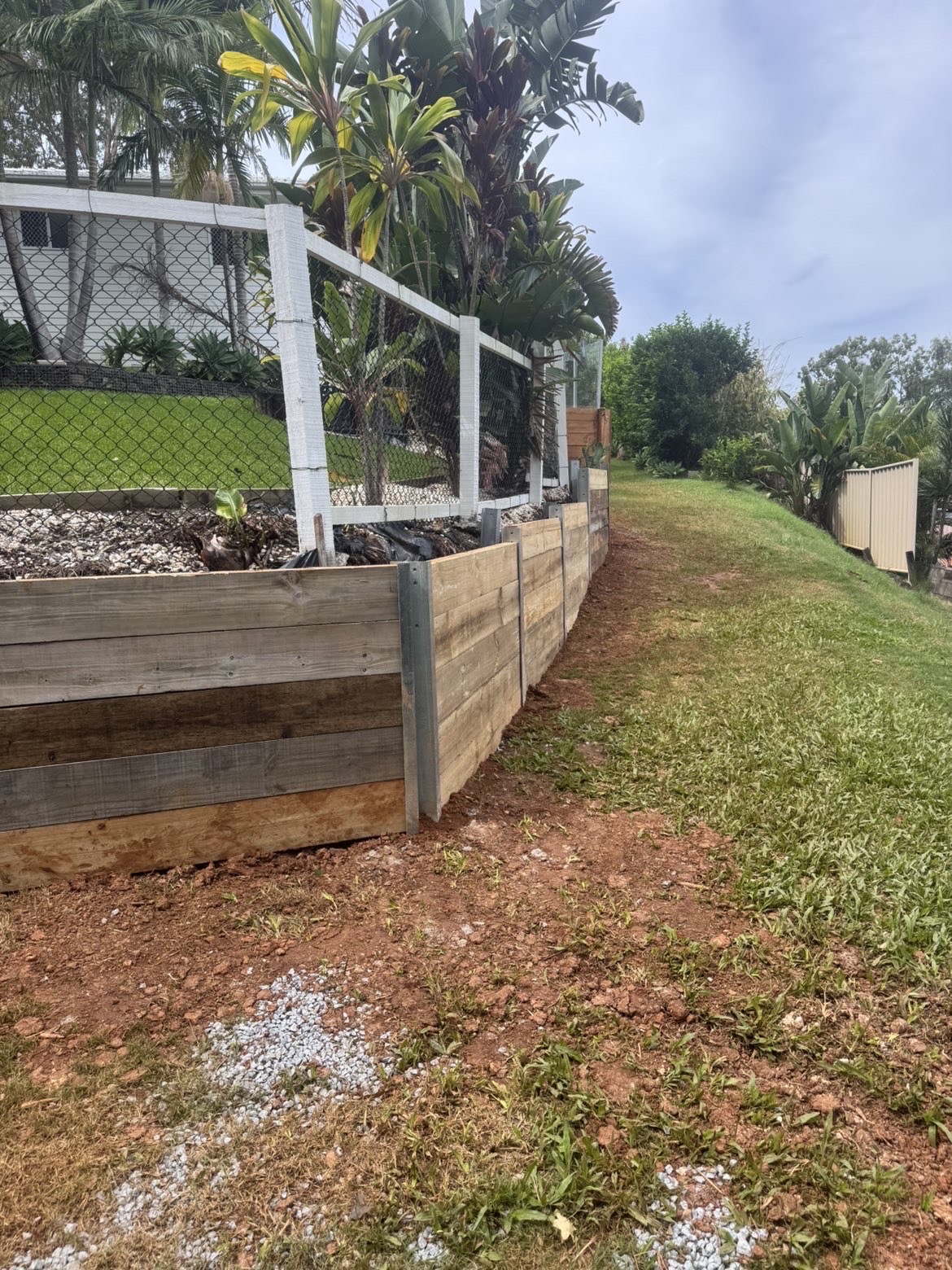 Long timber sleeper retaining wall running along a grassed side boundary of a Gold Coast property